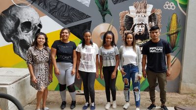 Grupo de novos alunos quilombolas e indígenas posa em frente a mural no Campus Anglo